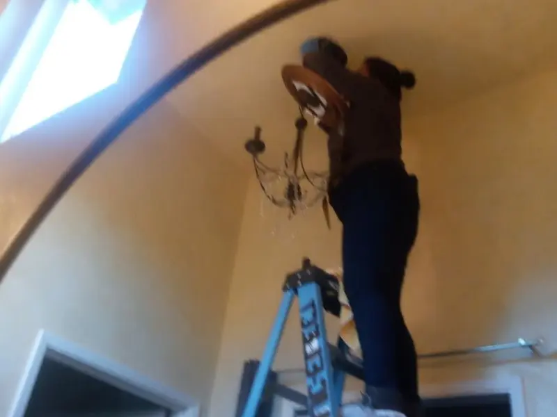 Electrician installing a chandelier in a Bart residence